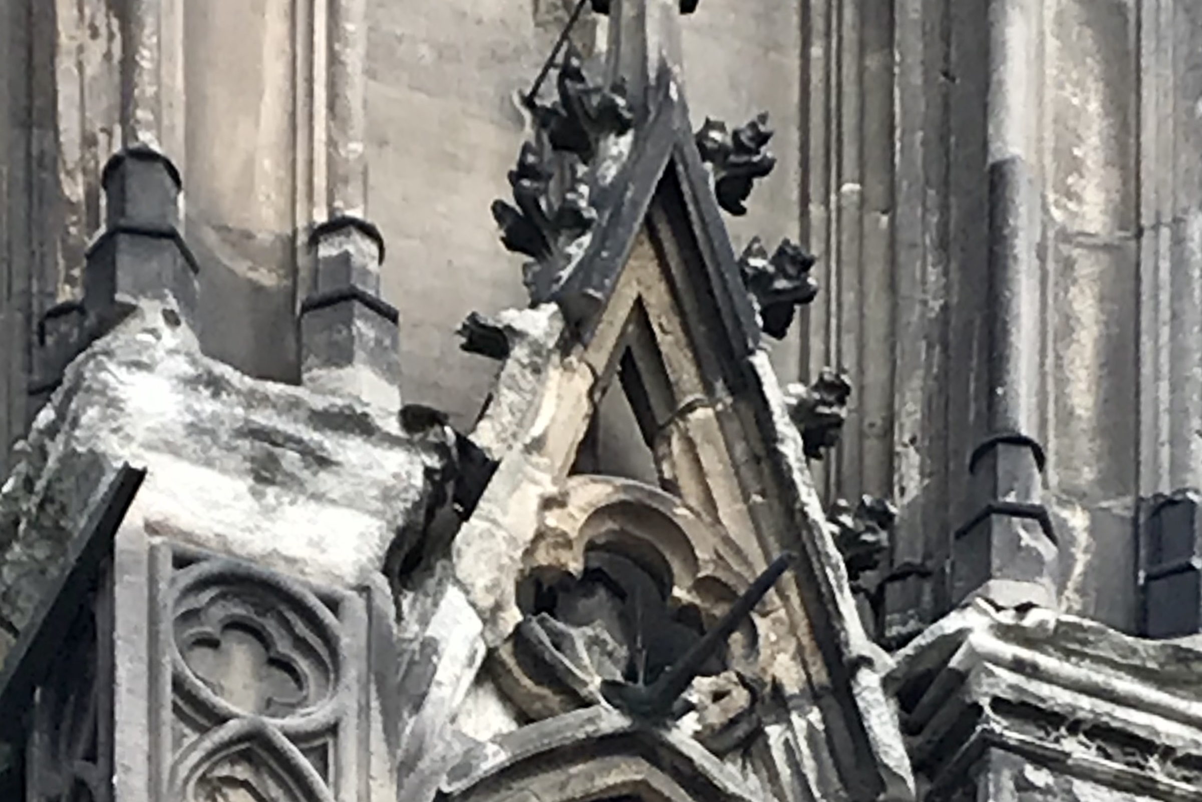 Verwitterter Sandstein an Fialen und Maßwerk einer gotischen Kathedrale mit dunklen Krusten und Abplatzungen