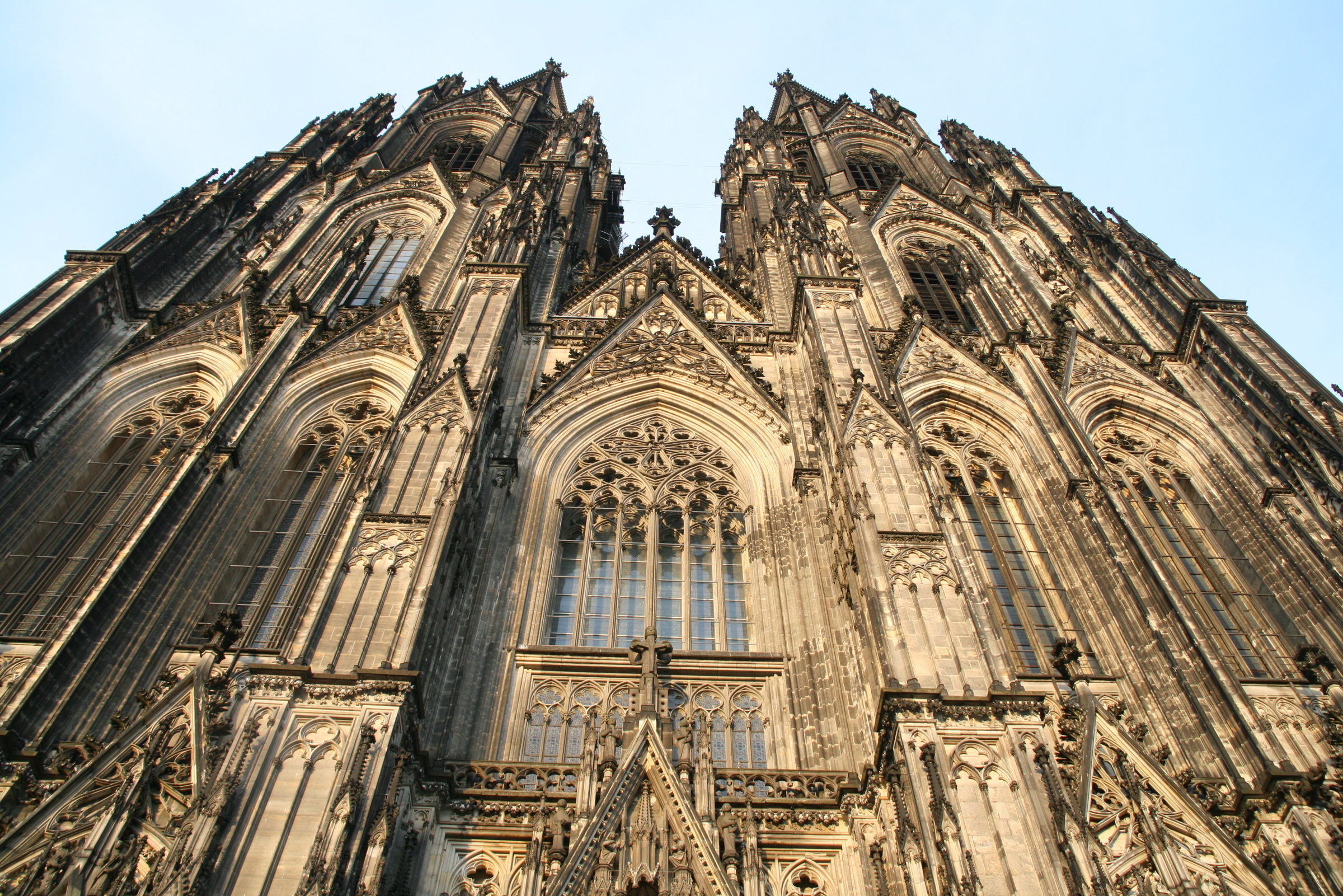 Westfassade einer gotischen Kathedrale aus dunkel verwittertem Sandstein von unten gesehen