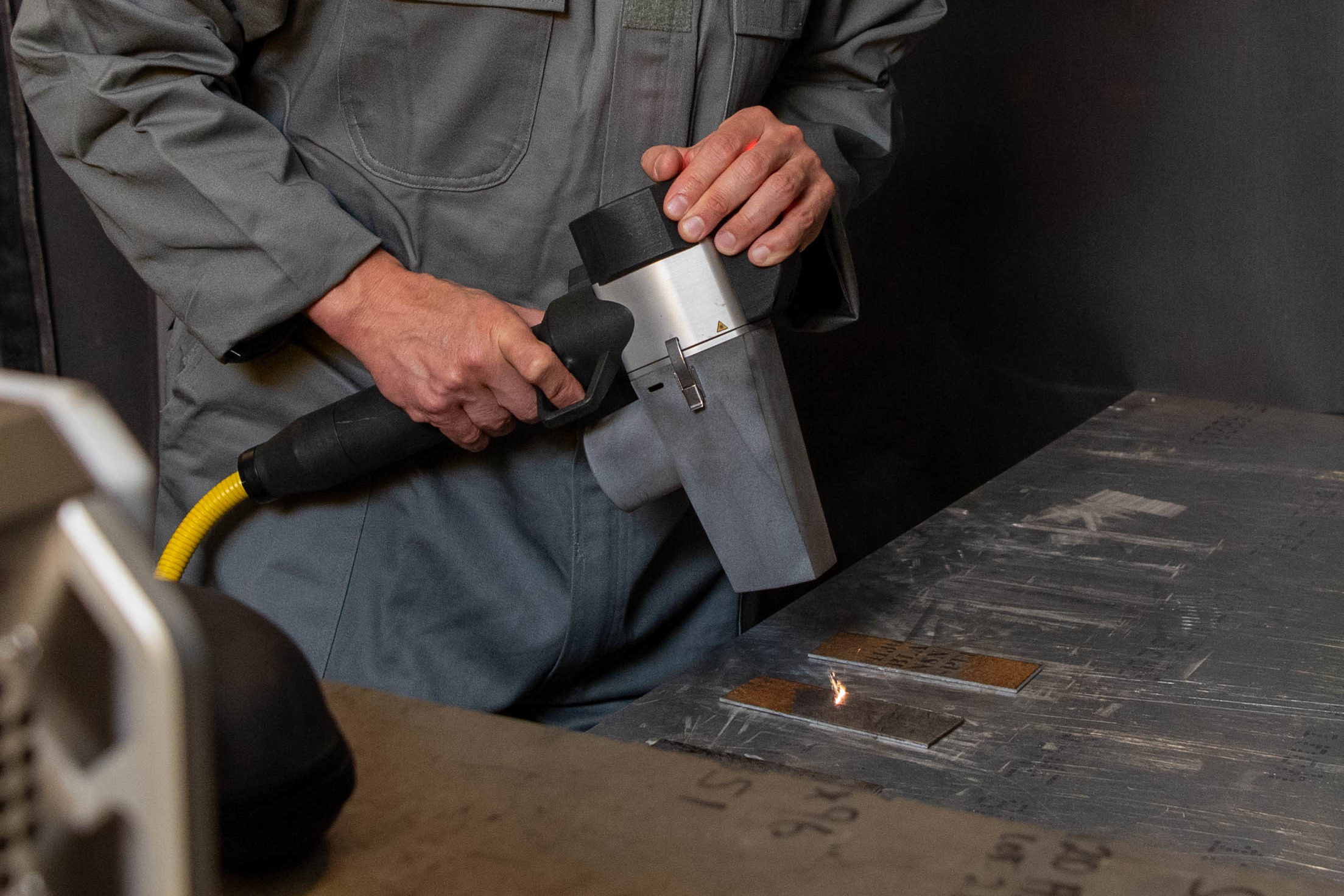 Handlaser über Metallstreifen, an einem Streifen grenzt blankes Metall direkt an die erhaltene braune Schicht