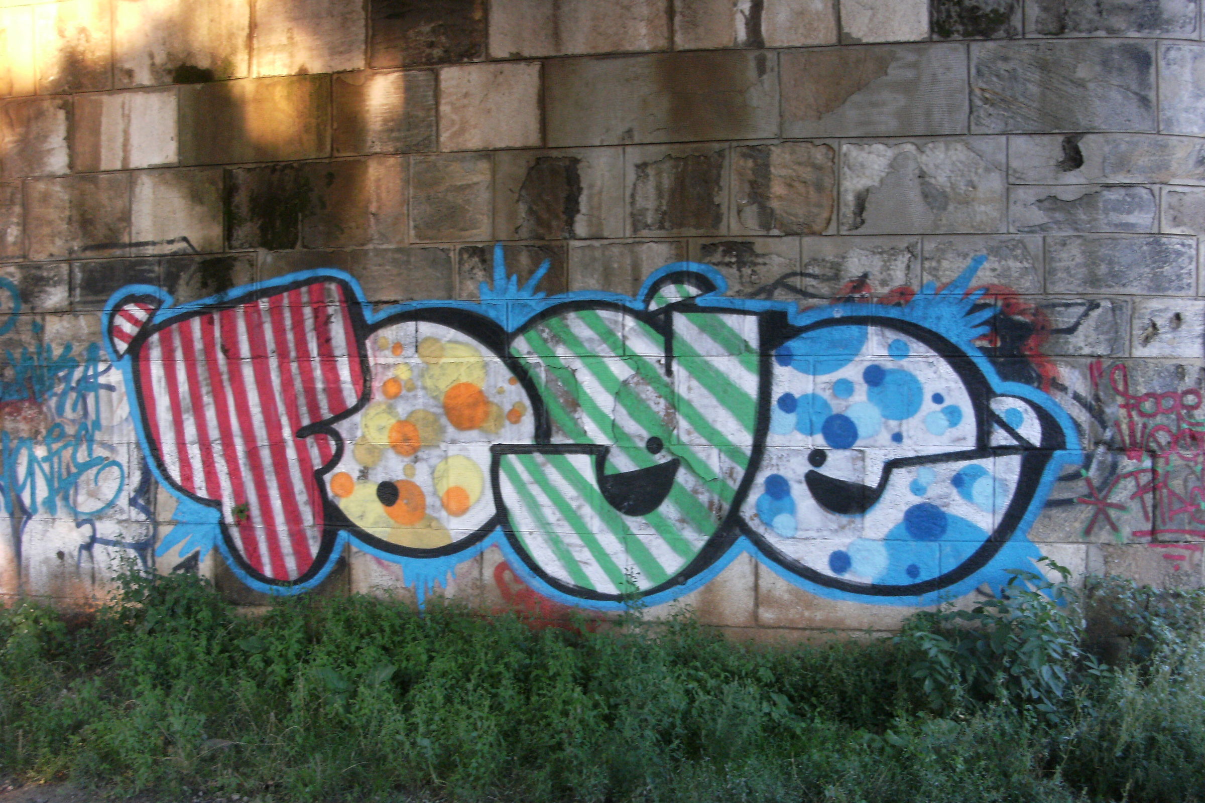 Großes buntes Graffiti auf einer Wand aus Sandsteinquadern, Fugen und Steinoberfläche sind gut zu erkennen