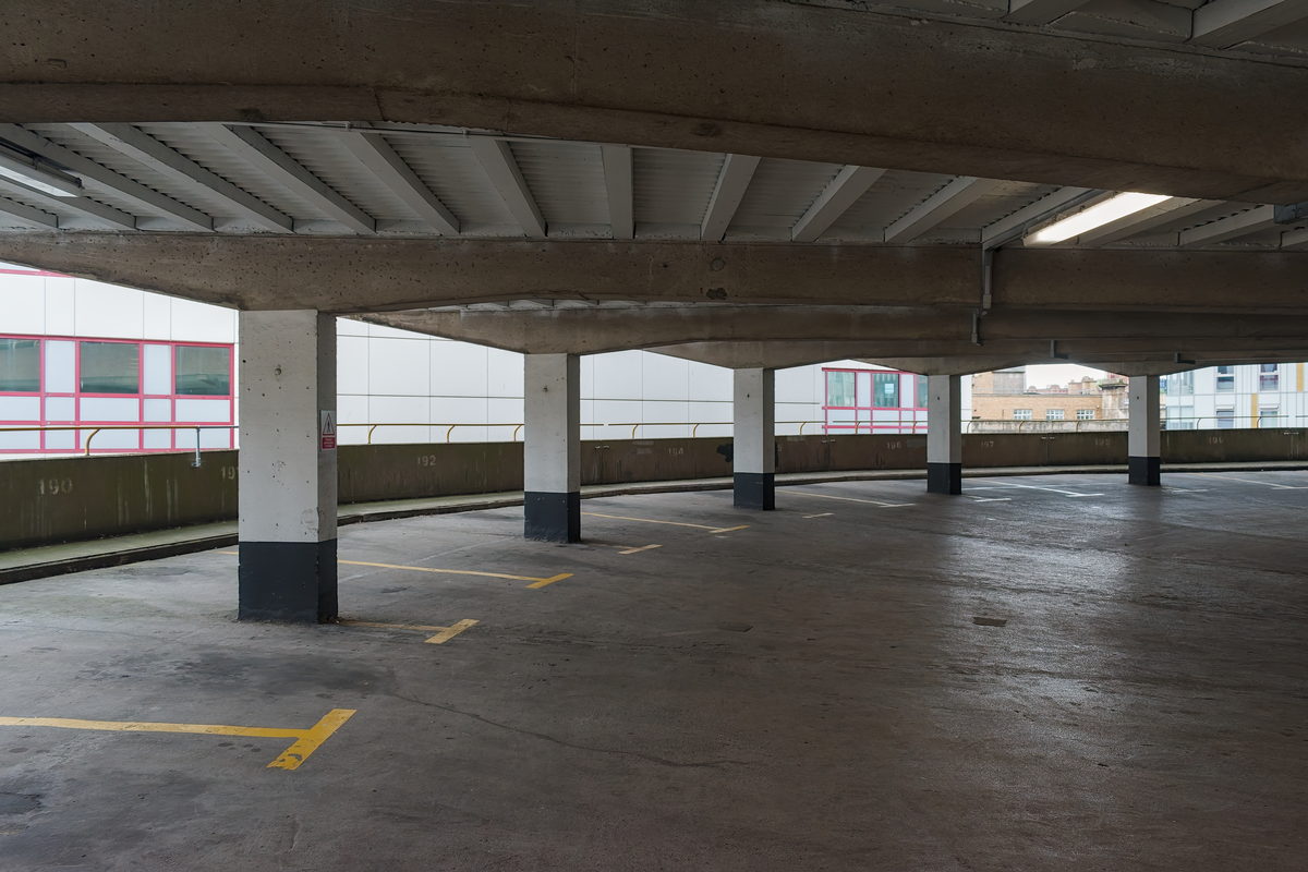 Leeres Parkdeck mit Betonstützen, Rippendecke und gelben Markierungen am Boden