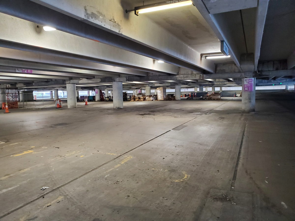 Parkdeck von innen: Betonträger und Stützen unter der Decke, an Träger und Decke helle und dunkle Flecken